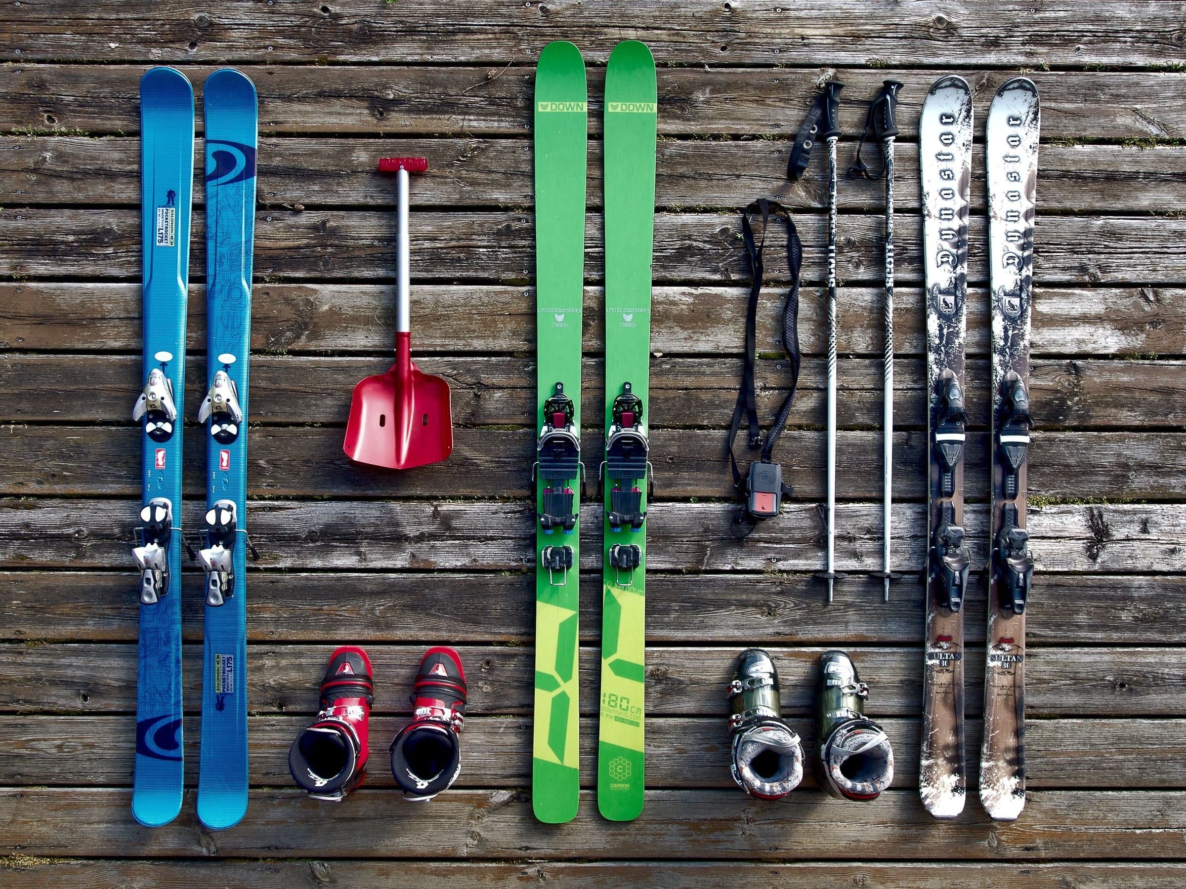 Ski boots, skis, and poles laid out for hire on a wooden deck